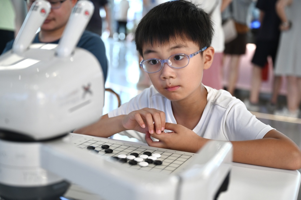 2026年7月19日，上海张江AI应用商店，小男孩正看着机器人，思考着它如何应对自己围棋的这一手。澎湃新闻记者 吴栋 图
